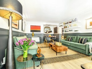A modern living room with a green sofa, a coffee table, a lamp, and a vase of flowers. - LivinParis | Luxury AC 3 Bedrooms Le Louvre III (Paris)