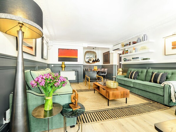 Una sala de estar moderna con un sofá verde, una mesa de centro, una lámpara y un jarrón de flores.