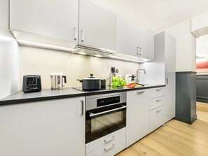 A modern kitchen with white cabinets, a built-in oven, a coffee maker, and a pot on the counter. - LivinParis | Luxury AC 3 Bedrooms Le Louvre III (Paris)