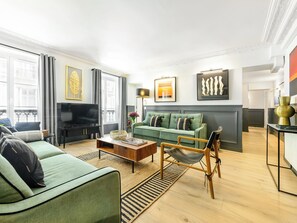 Uma sala de estar moderna com um sofá verde, uma mesa de centro e uma televisão.