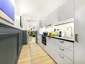 Una cocina moderna con armarios blancos, encimera negra y pileta de acero inoxidable.