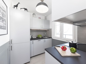 Una cocina moderna con armarios blancos, una encimera negra y un ventanal que proporciona luz natural.