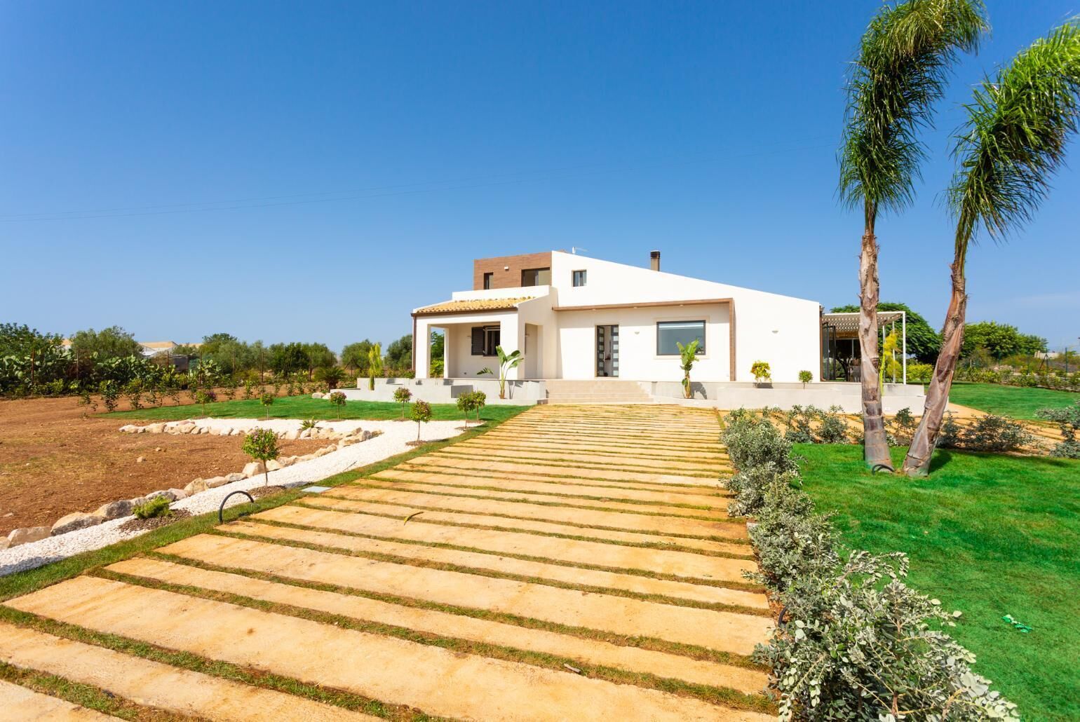 A modern house with a paved driveway leading to the entrance.