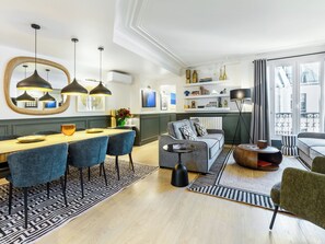 Ein modernes Wohnzimmer mit Essbereich, ausgestattet mit einer Couch, einem Couchtisch und einem Esstisch mit Stühlen.