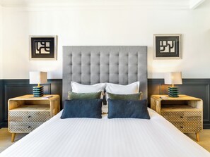Ein Hotelzimmer mit einem großen Bett, zwei Nachttischen und einem gepolsterten Kopfteil.