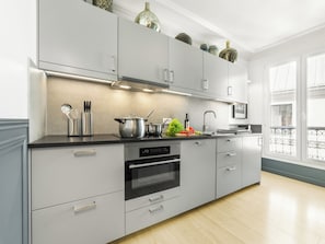 Eine moderne Küche mit grauen Schränken, Edelstahlgeräten und einem schwarzen Backofen.