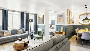 Uma sala de estar moderna com sofá, poltrona, mesa de centro e área de refeições.
