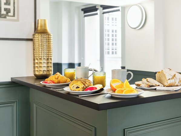 A breakfast setup with croissants, orange slices, and a loaf of bread on a counter.