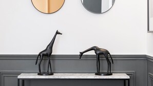 Ein Badezimmer mit Marmorplatte, zwei schwarze Tierminiaturen und zwei Wandspiegeln.
