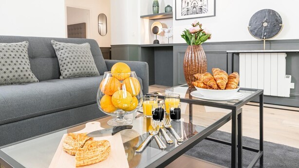 Ein modernes Wohnzimmer mit einem Glastisch, einer Couch und einer dekorativen Vase mit Blumen.