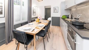 Eine moderne Küche mit Essbereich, mit einem Holztisch, schwarzen Stühlen und einer hängenden Leuchte.