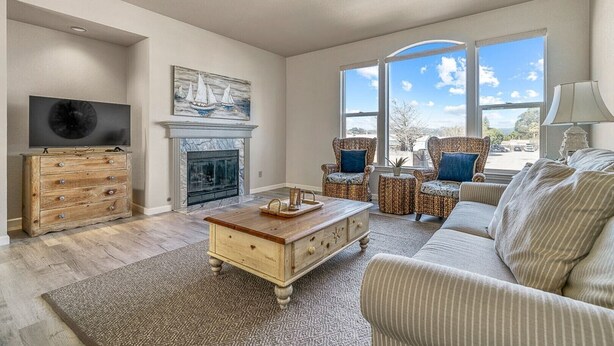 A living room with a fireplace, a television, wicker furniture, and large windows. - Classic Santa Cruz Getaway! (Santa Cruz)