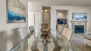 A spacious living room with a glass-top dining table, comfortable seating, a fireplace, and artwork on the walls. - Classic Santa Cruz Getaway! (Santa Cruz)