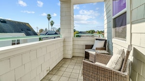 A balcony with a tiled floor, wicker furniture, and a view of the surrounding area. - Classic Santa Cruz Getaway! (Santa Cruz)