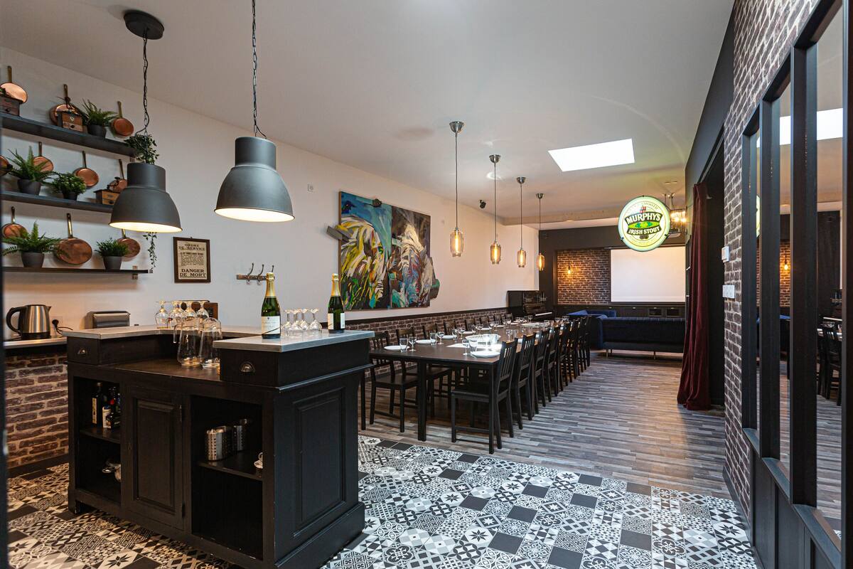 Un restaurante moderno con un amplio comedor, suelo con estampado blanco y negro, y diversas plantas y obras de arte en las paredes.