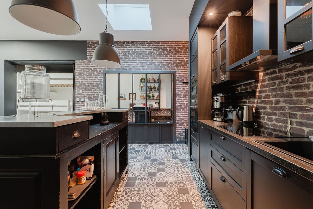 A modern kitchen with a brick wall, a central island, and a skylight.