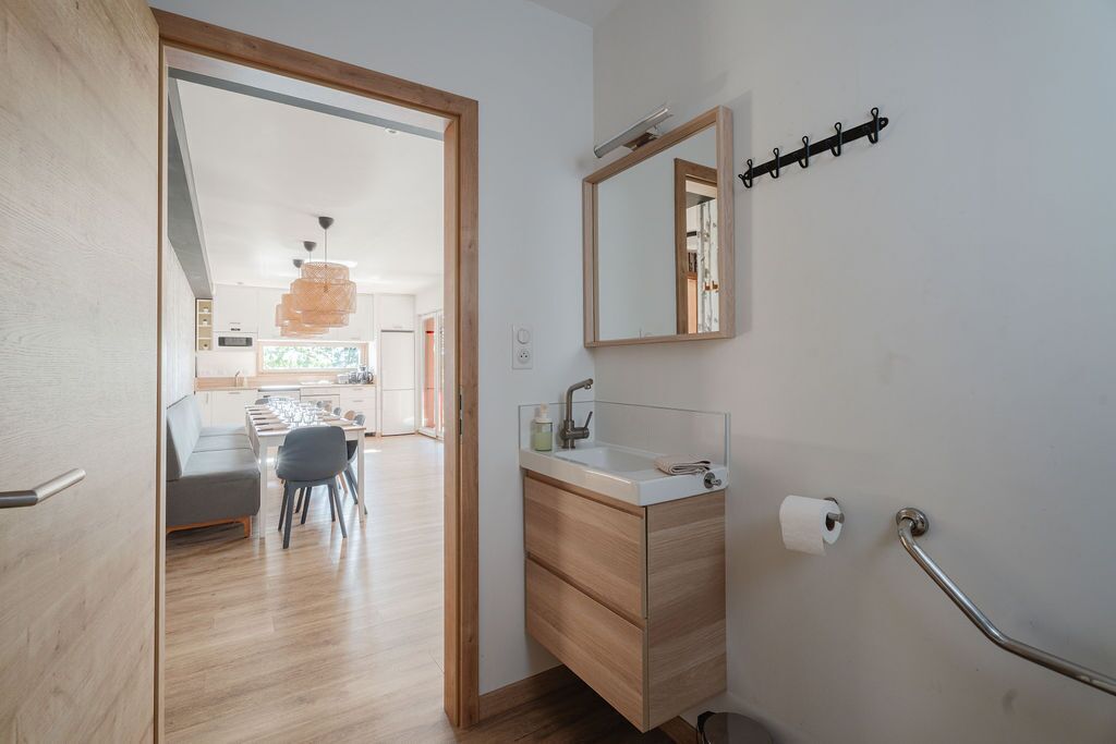 A modern bathroom with a wooden vanity, a mirror, a towel rack, and a toilet paper holder.