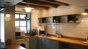 A compact kitchen with a washing machine, microwave, and coffee maker. - Hostel Cleo Seoul Hongdae (Seoul)