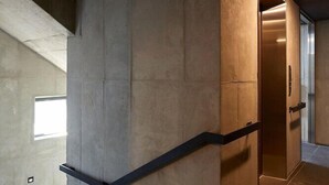 A modern interior with a concrete staircase, a wooden door, and a tiled floor. - Hostel Cleo Seoul Hongdae (Seoul)