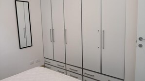 A bedroom with a bed, a wardrobe with multiple doors and drawers, and a mirror on the wall. - Villa Azzurra facing the sea (SAN VITO LO CAPO)
