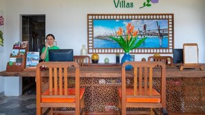 A reception desk with a woman seated behind it, a framed painting of a tropical scene, and the name 'CAT TUONG Villas' on the wall. - Lemongrass Homestay (Hoi An)