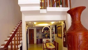 A spacious living area with a dining table and chairs, a staircase, and a large vase. - Lemongrass Homestay (Hoi An)