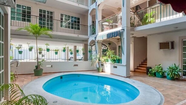 Une piscine intérieure à plusieurs niveaux, dotée de balcons, de plantes en pot et d’un escalier.