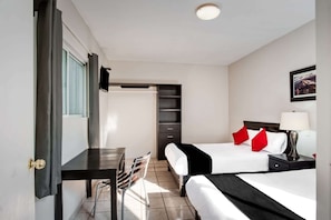 A hotel room with two beds, a desk, a chair, a TV, and a picture on the wall.