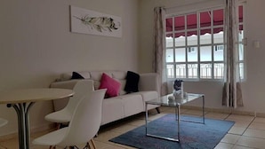 Un salon avec un canapé, des fauteuils, une table basse et une fenêtre avec des rideaux.