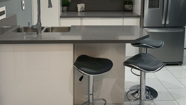 Eine moderne Küche mit einem Edelstahl-Kühlschrank, einem Einbauofen, einer Spüle und zwei Barhocker.