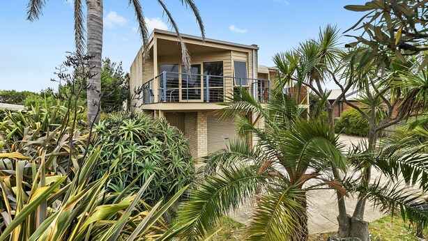 A two-story building with a balcony, surrounded by tropical plants. - Coastal Home away from Home (Torquay)