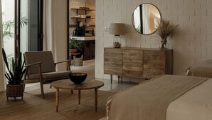 Et moderne soveværelse med en trækommode, et rundt spejl, et natbord og en stor seng.