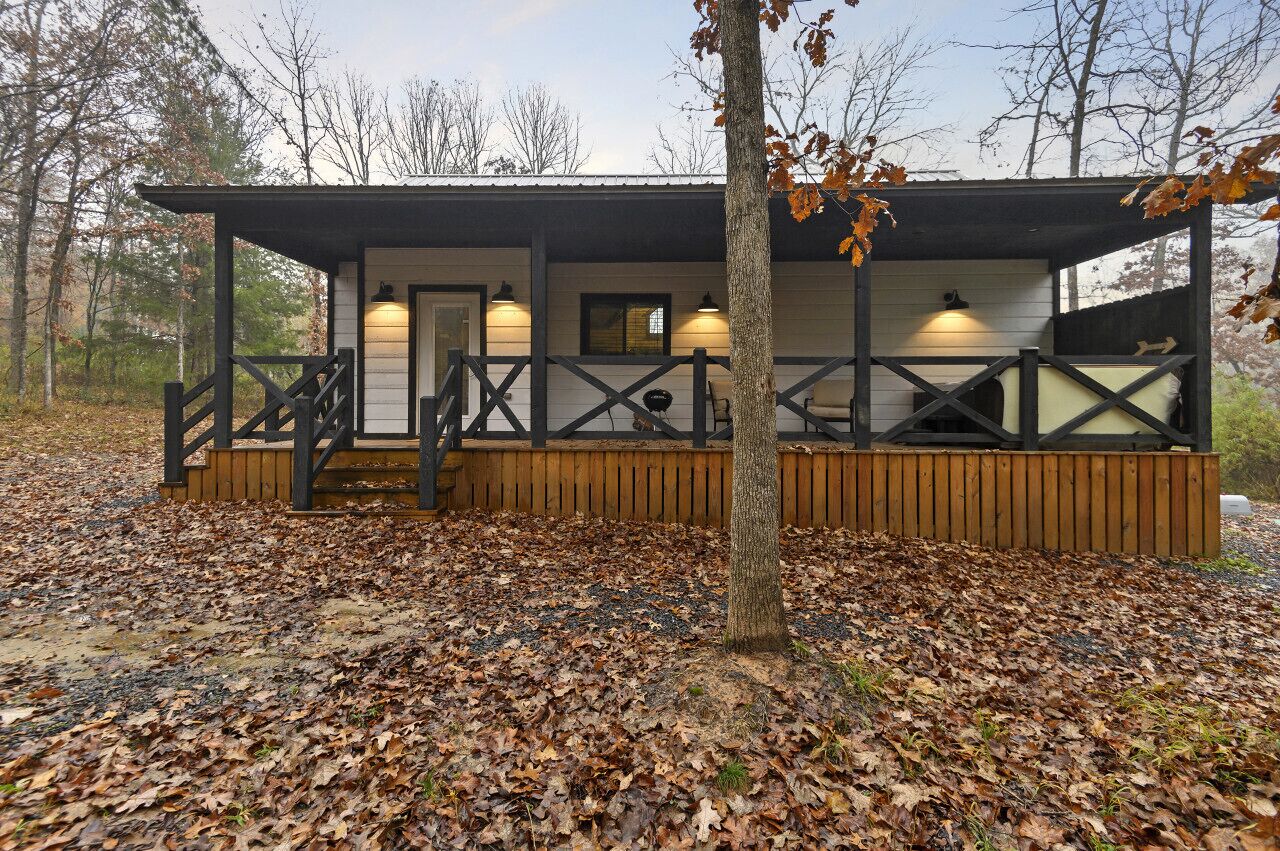 A cabin with a wooden deck, a staircase, and a covered porch area.