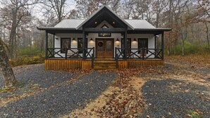 Ein Blockhaus mit Veranda, einer Haustür mit einem Kranz und einem Schild.