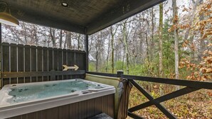 Ein Whirlpool mit einer Holzterrasse und Blick auf einen Wald.