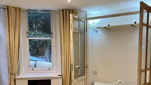 A bedroom with a bed, a window, a fireplace, and a wooden ceiling.