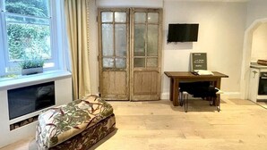 A room with a sofa, a TV, a wooden table, and a double door with frosted glass panels.
