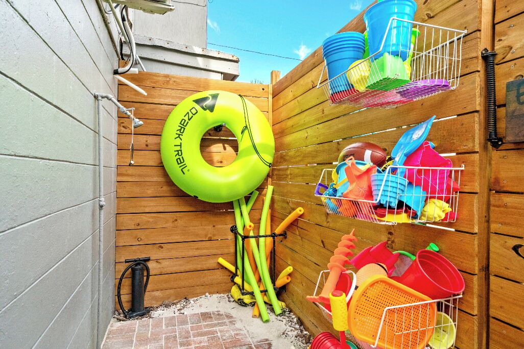 Ein Holzzaun mit Schwimmbadnudel, Gartenschlauch und Plastikbehältern.