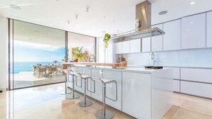 A modern kitchen with a large island, bar stools, and a view of the ocean.