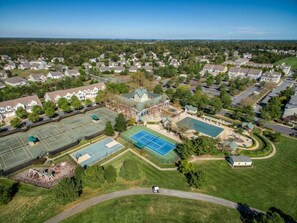 An aerial view of a residential area with houses, a tennis court, and a swimming pool.