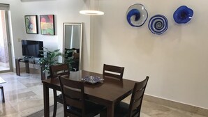 Un coin repas avec une table en bois et quatre chaises, un téléviseur et des œuvres d’art décoratives au mur.