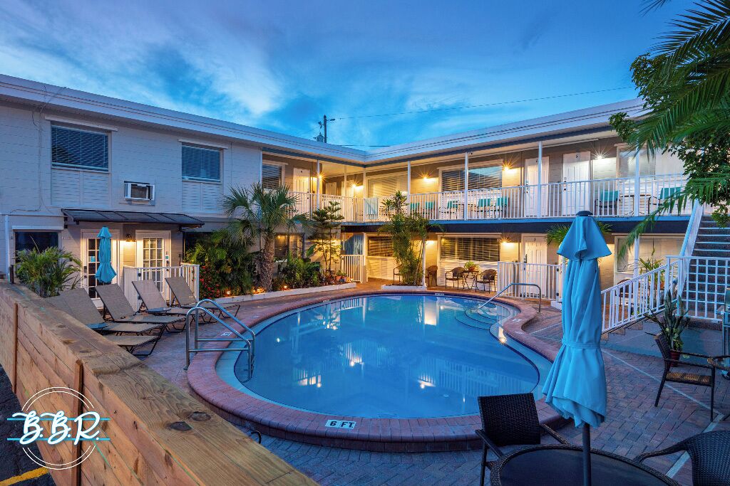 A hotel with a pool, outdoor seating, and a covered patio area.