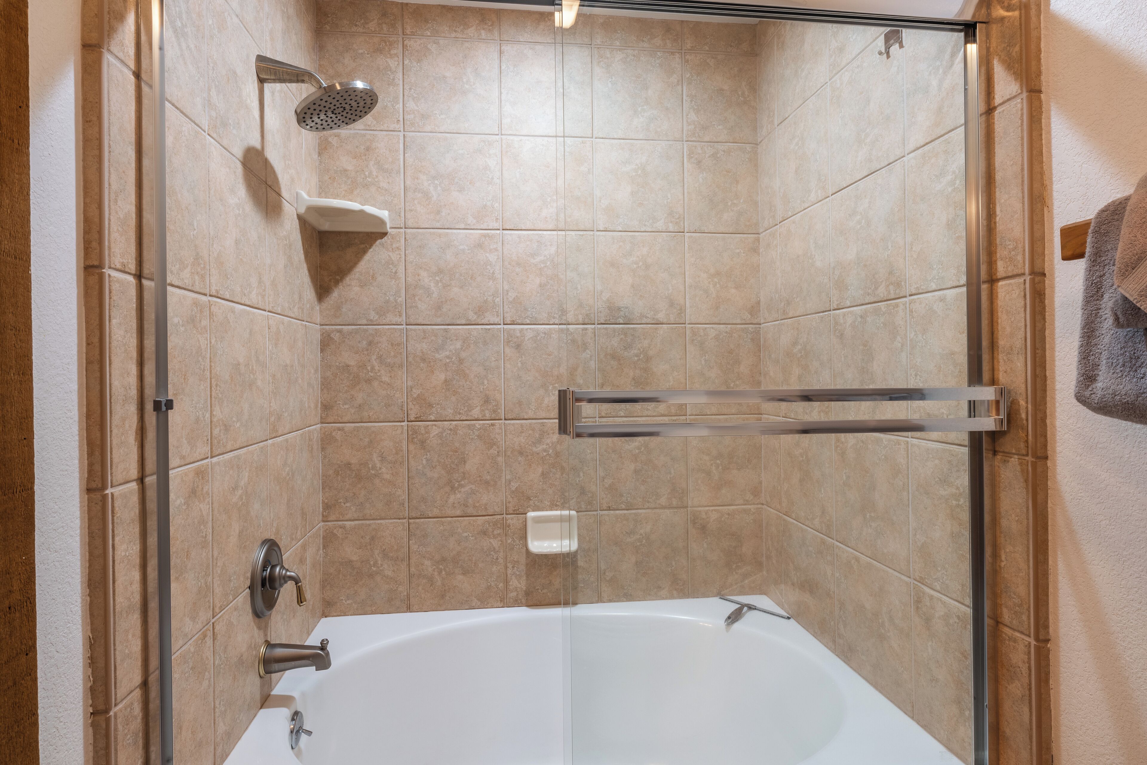 A modern bathroom with a glass-enclosed shower, a white bathtub, and a towel rack.