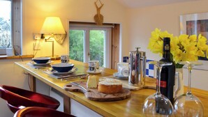 A kitchen with a wooden countertop, a coffee maker, a bottle of wine, and a vase of flowers. - A lovely open plan detached cottage in a rural location. (Near Sawrey, near Ambleside)