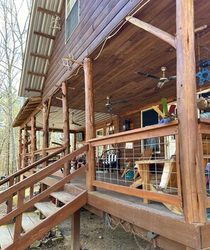 A wooden cabin with a covered porch, a staircase, and a view of the surrounding forest. - Anderson Paradise Cabin in Albert Pike Recreational Area, Caddo Gap Arkansas (Caddo Gap)