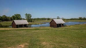 Two wooden barns with metal roofs, a small pond, and a clear blue sky. - Private Country Getaway (Fitzpatrick)