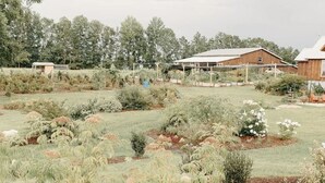 A rural landscape with a large barn, a greenhouse, and a variety of cultivated plants. - Private Country Getaway (Fitzpatrick)