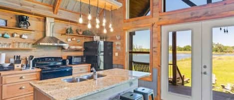Una cocina amplia con una isla grande, taburetes de bar y vistas al exterior.