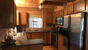 Una cocina con gabinetes de madera, un refrigerador de acero inoxidable, un microondas y una estufa.