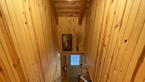 Una escalera de madera con barandilla, que lleva a una puerta con ventanal.